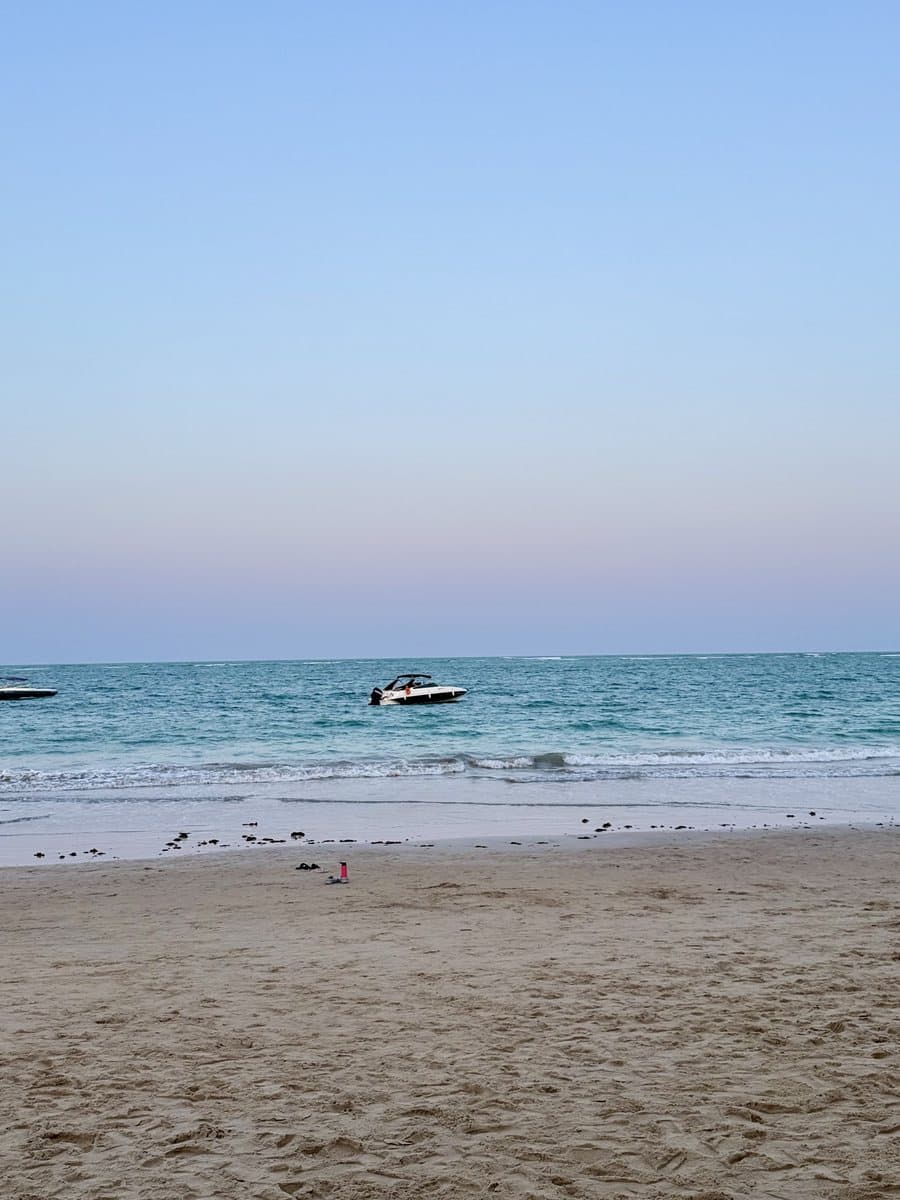 The beach at dusk: calm sea, a small boat, and sand